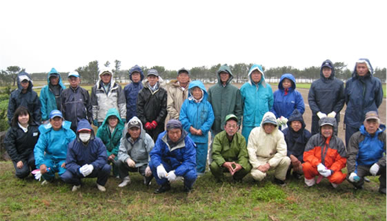 防風林を背景に参加者による集合写真